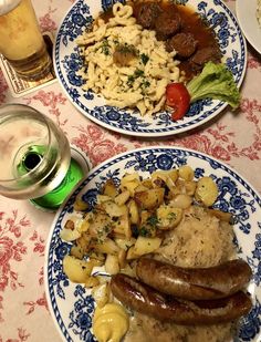 two blue and white plates with sausages, macaroni and cheese on them