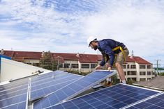 a man on top of a roof installing solar panels