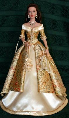 a barbie doll wearing a gold and white dress with flowers on it's skirt