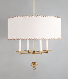 a chandelier with three lights hanging from it's sides and a white lamp shade