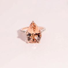 an orange and white diamond ring sitting on top of a white surface with diamonds around it