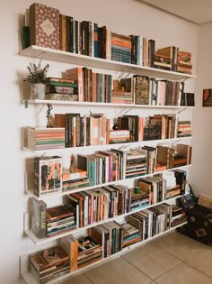 a bookshelf filled with lots of books next to a wall mounted planter