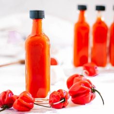 there are several bottles with hot sauce in them on the table next to red peppers