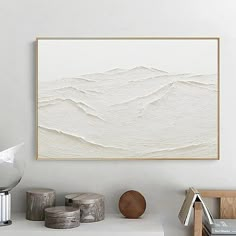 an abstract painting hangs on the wall above a shelf