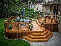 a wooden deck with steps leading up to the patio and dining table in the back yard