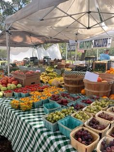 an open air market with lots of fresh fruits and vegetables in baskets on the tables