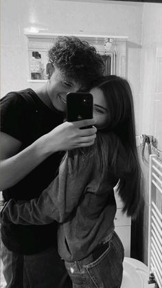 a man and woman are taking a selfie in the bathroom while looking at their cell phone