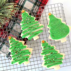 three decorated christmas tree cookies on a cooling rack