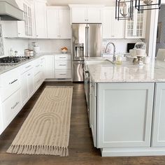 a large kitchen with white cabinets and marble counter tops, along with an area rug on the floor