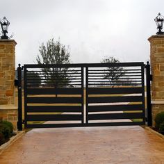 an iron and wood gate with brick pillars