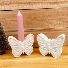 two candles are sitting next to each other on a shelf near a small christmas tree