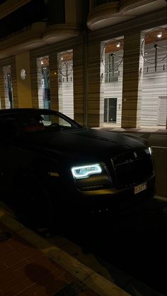 a black car parked in front of a building at night