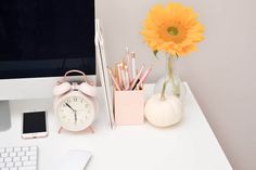 an office desk with a computer, phone and sunflower