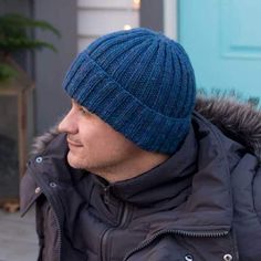 a man wearing a blue hat while standing in front of a door and looking off to the side