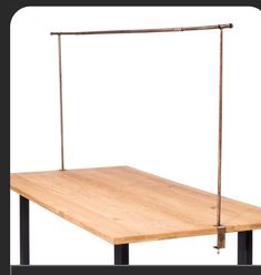 a wooden table with two black metal legs and a square wood board on the bottom