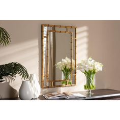 a vase with white flowers sitting on top of a wooden table next to a mirror