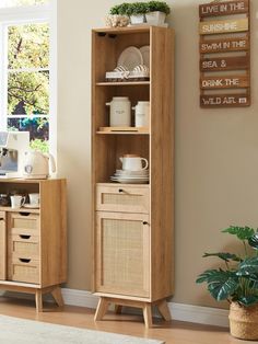 a wooden cabinet sitting next to a window filled with plants and dishes on top of it