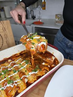 a woman is cutting into a lasagna dish