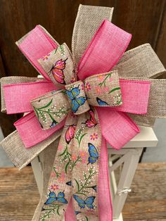 a pink bow with butterflies on it sitting on a white chair in front of a wooden wall