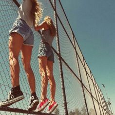 two people are standing on the edge of a fence and one is holding onto another person's leg