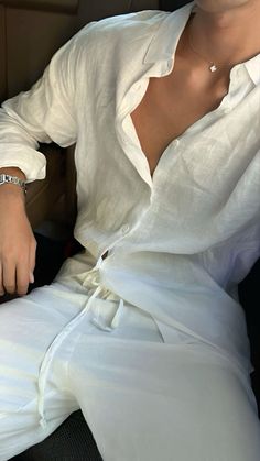 a woman sitting in the back seat of a car wearing a white shirt and pants