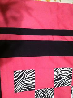 a pink and black quilt with zebra print squares on the front, along with two smaller square holes in the middle