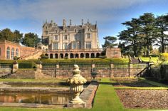 a large castle like building sitting next to a lush green park filled with lots of trees