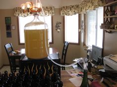 a table with bottles on it and a lamp hanging from the ceiling in front of two windows