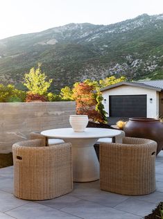 an outdoor table and chairs on a patio with mountains in the backgrouund