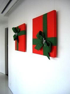 two red and green wrapped gift boxes hanging on the wall next to each other with bows