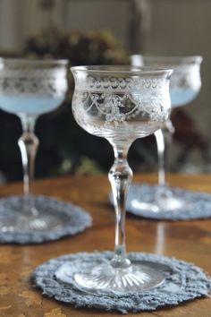 three glass goblets sitting on top of a wooden table