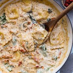 a skillet filled with ravioli, spinach and cheese covered in cream sauce