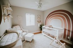 a baby's room with a white crib, chair and large wall mural