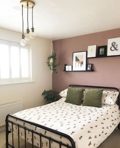 a bed room with a neatly made bed and pictures hanging on the wall above it