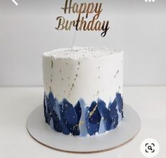 a white cake with blue icing and gold sprinkles that says happy birthday