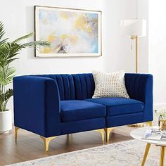 a living room with a blue couch and coffee table in front of a painting on the wall