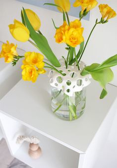 a vase filled with yellow flowers on top of a white table