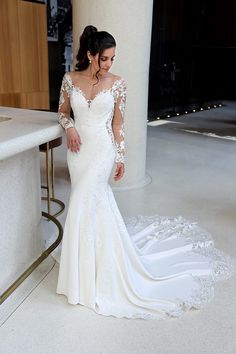 a woman in a white wedding dress standing next to a counter with her hands on her hips