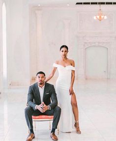 a man and woman posing for a photo in front of a white room with columns