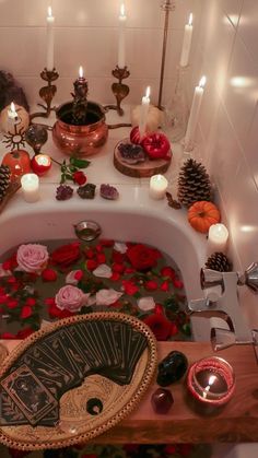 a bathtub filled with candles and flowers on top of a wooden table next to other items