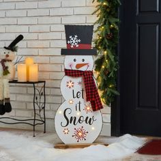 a snowman with a hat and scarf standing in front of a christmas door decoration