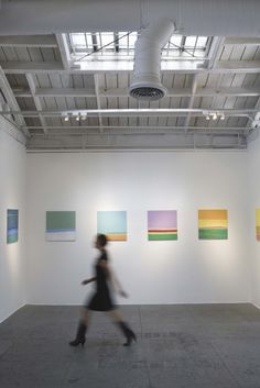 a woman is walking in an art gallery with paintings on the wall and ceiling above her