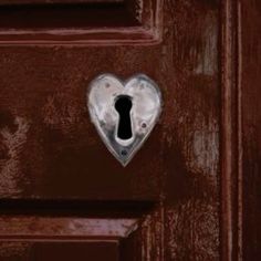 a heart shaped keyhole on a brown door with a metal lock in the middle