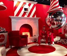 two men sitting in front of a red and white room filled with shiny balls, mirrors and furniture