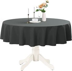 a round table with a black tablecloth and white pedestals is shown in front of a flower vase