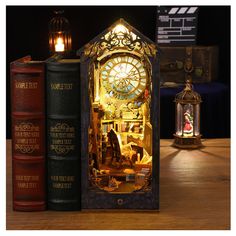 an illuminated clock sitting on top of two books next to a lamp and some candles