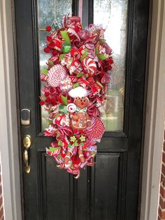 a christmas wreath hanging on the front door with candy canes and candies around it