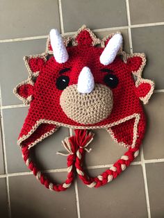 a crocheted animal hat with horns on the head sits on a tile floor