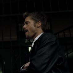 a man in a suit and tie standing next to a fence