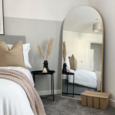 a bedroom with a bed, mirror and two nightstands in front of the bed